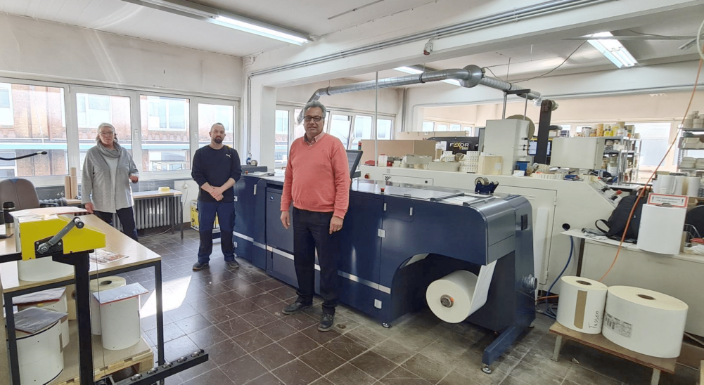 Geschäftsführer Ronald Kuhls (r.) zusammen mit Mitarbeitern vor der neuen AccurioLabel 230 (Quelle: ITA Systeme)