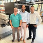 Sascha Zapf (Vertriebsleiter bei MPrint) und David van Loo (Vertriebs- und Marketingleiter bei MPrint)  zusammen mit Ahmed Türkmen (Vertriebsleiter bei Vetaphone) vor einer MLabel 3-Anlage von am Firmensitz in Baiersbronn (Quelle: The Publicity Studio)