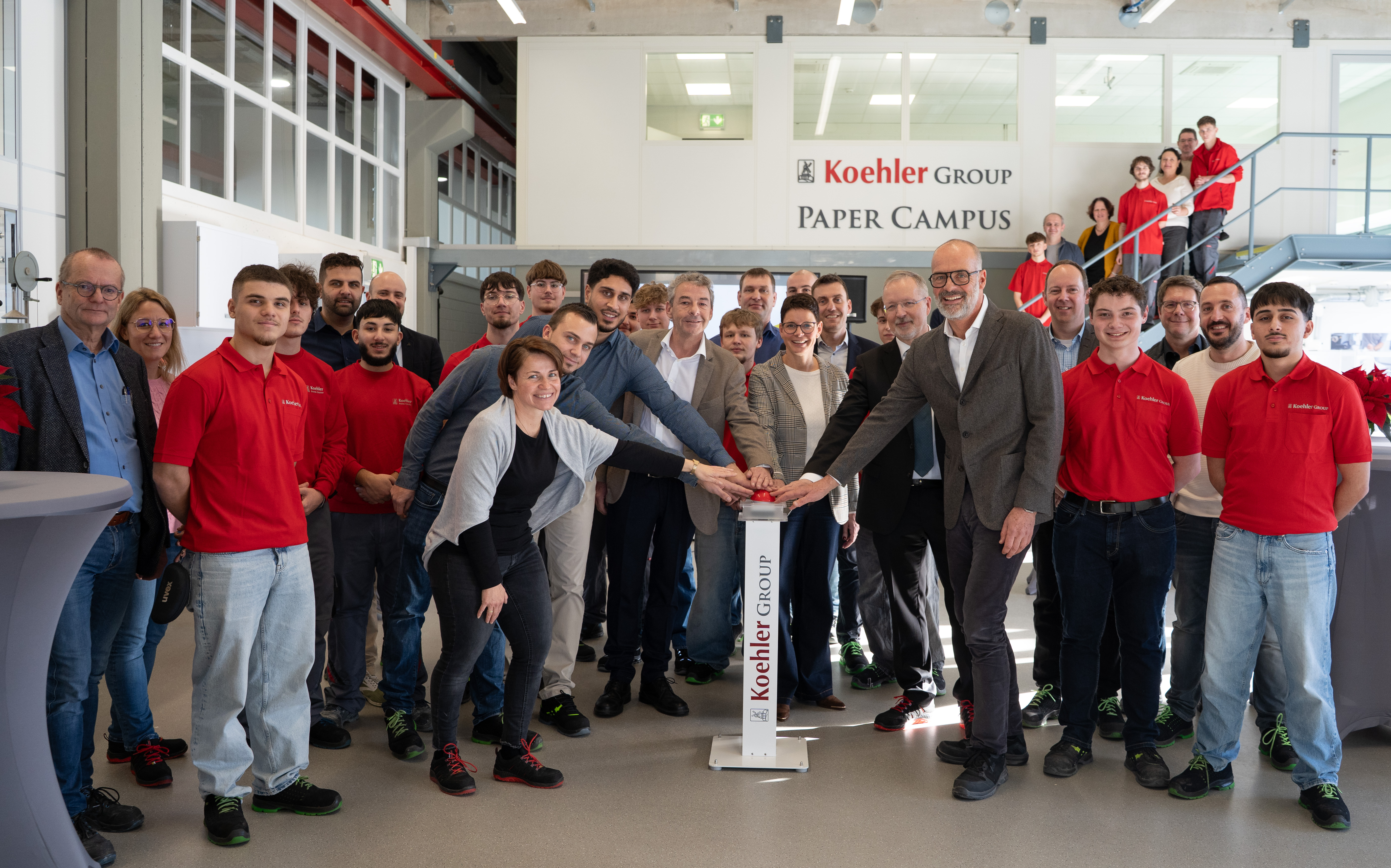 Die Beteiligten am Koehler Group Paper Campus zusammen mit den Auszubildenden bei der feierlichen Eröffnung. Am Buzzer v.l.n.r. Birgit Braun (Projektleiterin Planung Bau – Zentrale Anlagentechnik), Bernd Heidenreich (Ausbilder Papiertechnik), Faruk Tascioglu (Ausbilder Papiertechnik), Kai Furler (Vorstandsvorsitzender), Simone Wölfle (Leiterin Ausbildung und Personalentwicklung), Frank Lendowski (Vorstand Finanzen und Verwaltung) und Dr. Stefan Karrer (Vorstand Technik) (Quelle: Koehler-Gruppe)