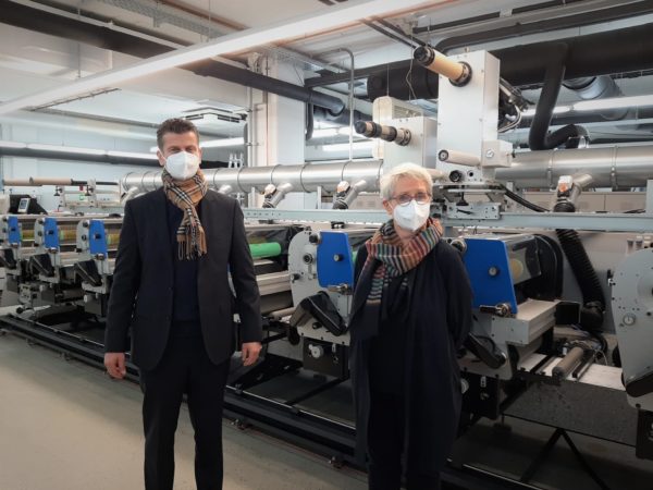 Brigitte Alers, Geschäftsführerin von bentlage-label GmbH (rechts) mit Michael Koch von Heidelberg Deutschland (links) vor der im Dezember 2020 installierten Gallus ECS 340, die die Kapazität und das Produktportfolio erweitert (Quelle: Gallus)